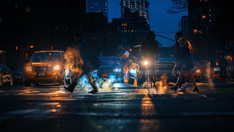 People crossing street in front of waiting cars.